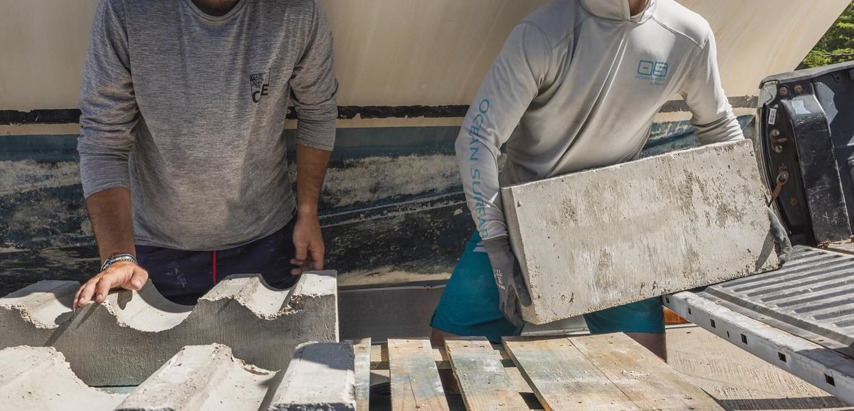 Team members lifting cast concrete modules from a pallet to load them for transport